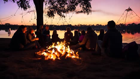 gathering around a warm fire by the lake during twilight with friends