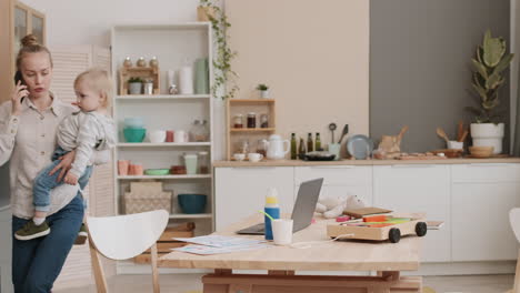 woman carrying toddler and working home
