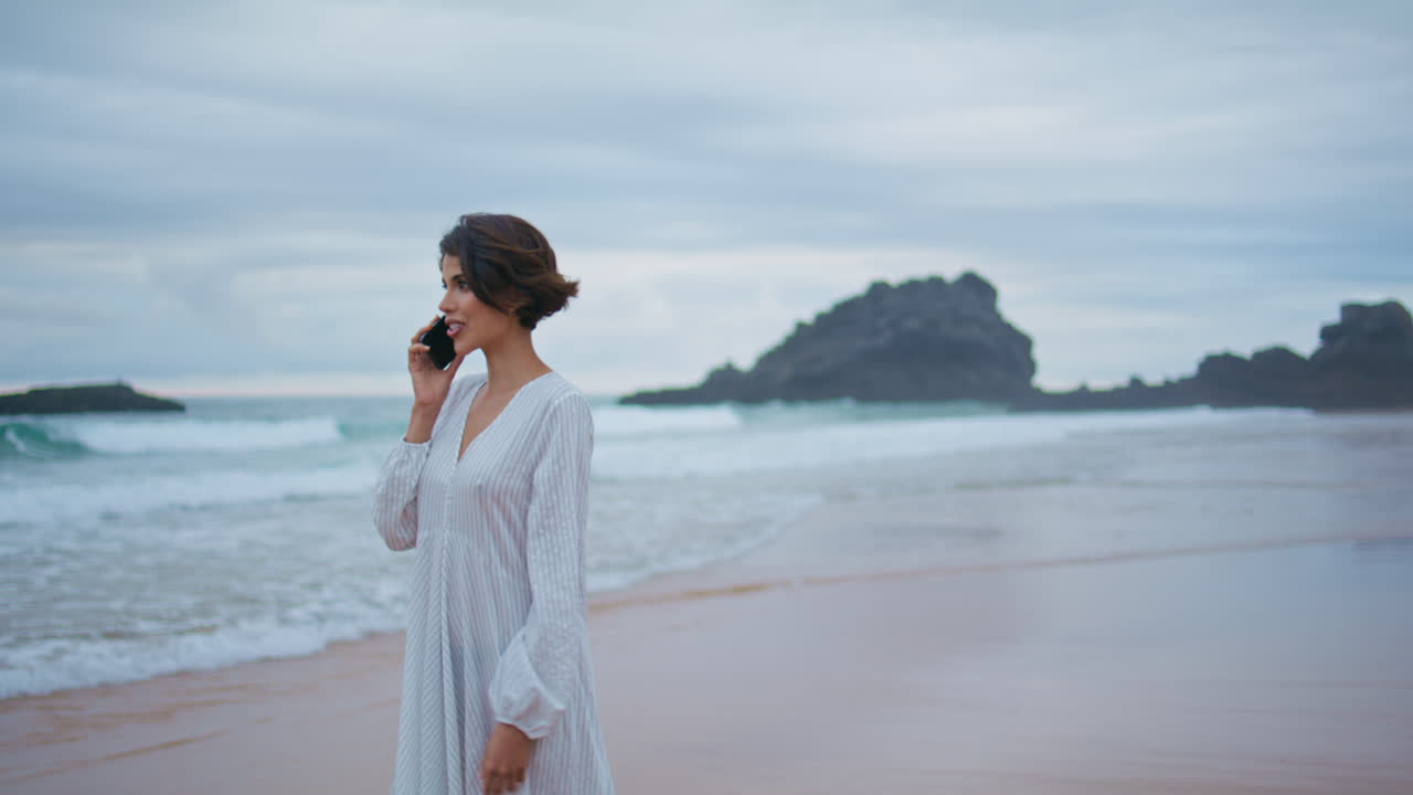 웃는 모델은 바위가 많은 열대 해변에서 셀을 호출합니다. 해변에 가는 휴가 소녀