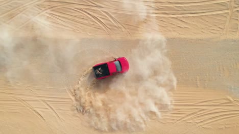 Red-truck-drifting-doughnuts-in-the-desert,-drone-top-view