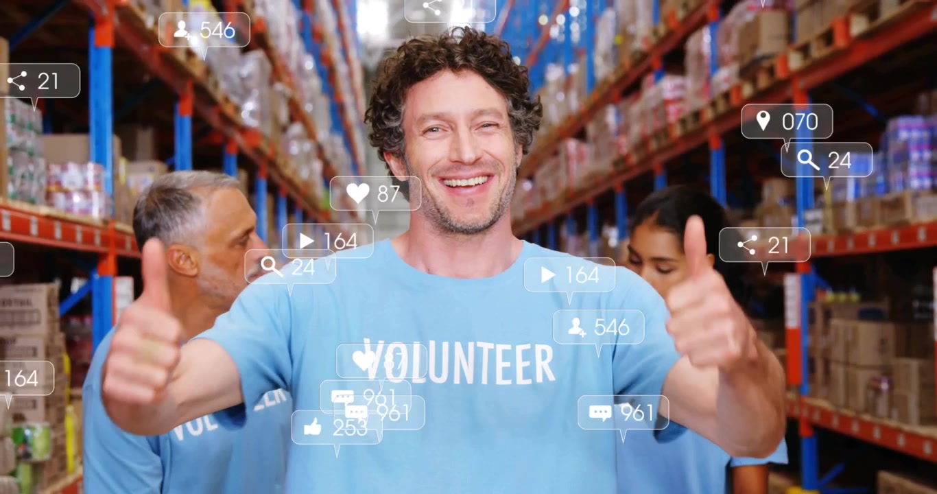 Volontario che indica una maglietta e avvia icone social fluttuanti che aumentano in un magazzino logistico