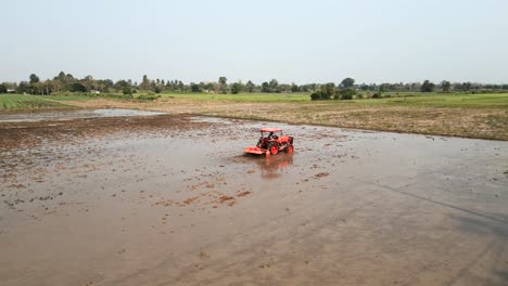 a tractor working in a flooded field, preparing the land for cultivation