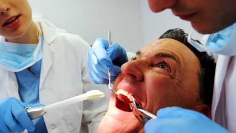 dentistas examinando a un paciente masculino con herramientas
