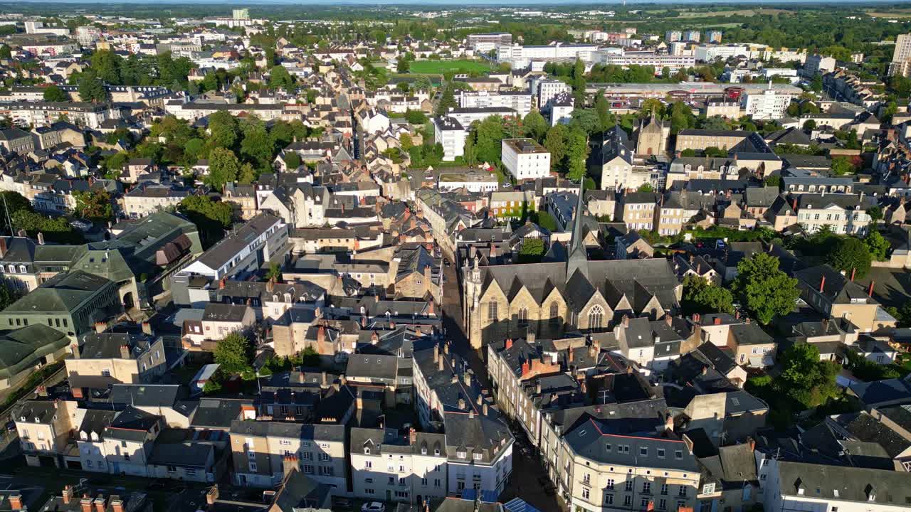 A drone pullback shot shows the city of Laval, highlighting Saint-Vénérand Church, surrounding streets, and residential buildings as the drone moves backward