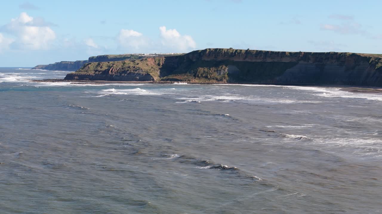 aerial drone footage of Cayton Bay looking towards Filey and ocean and big waves