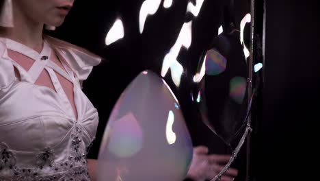 close-up: girl does tricks with soap bubbles. she plays with large bubbles, using her fingers