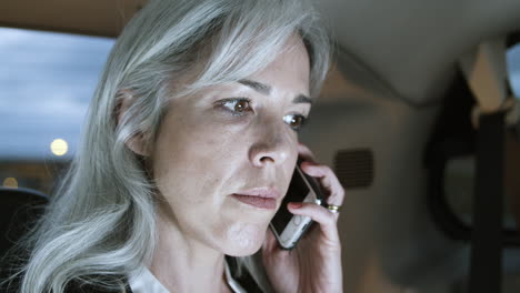 close up of woman in suit talking on phone in a car