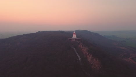 aerial drone shot of a hindu temple on hill top with stairs leading to it during sunset time in a village of gwalior in madhya pradesh india