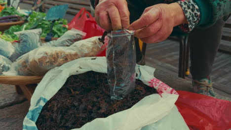 a person fills a plastic bag with soil at a market stall in wuzhen, china