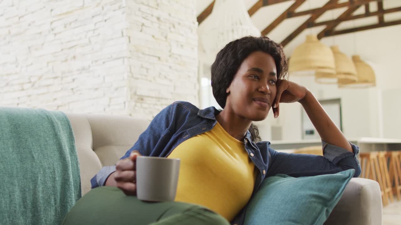 video de una feliz mujer afroamericana en el sofá viendo la televisión