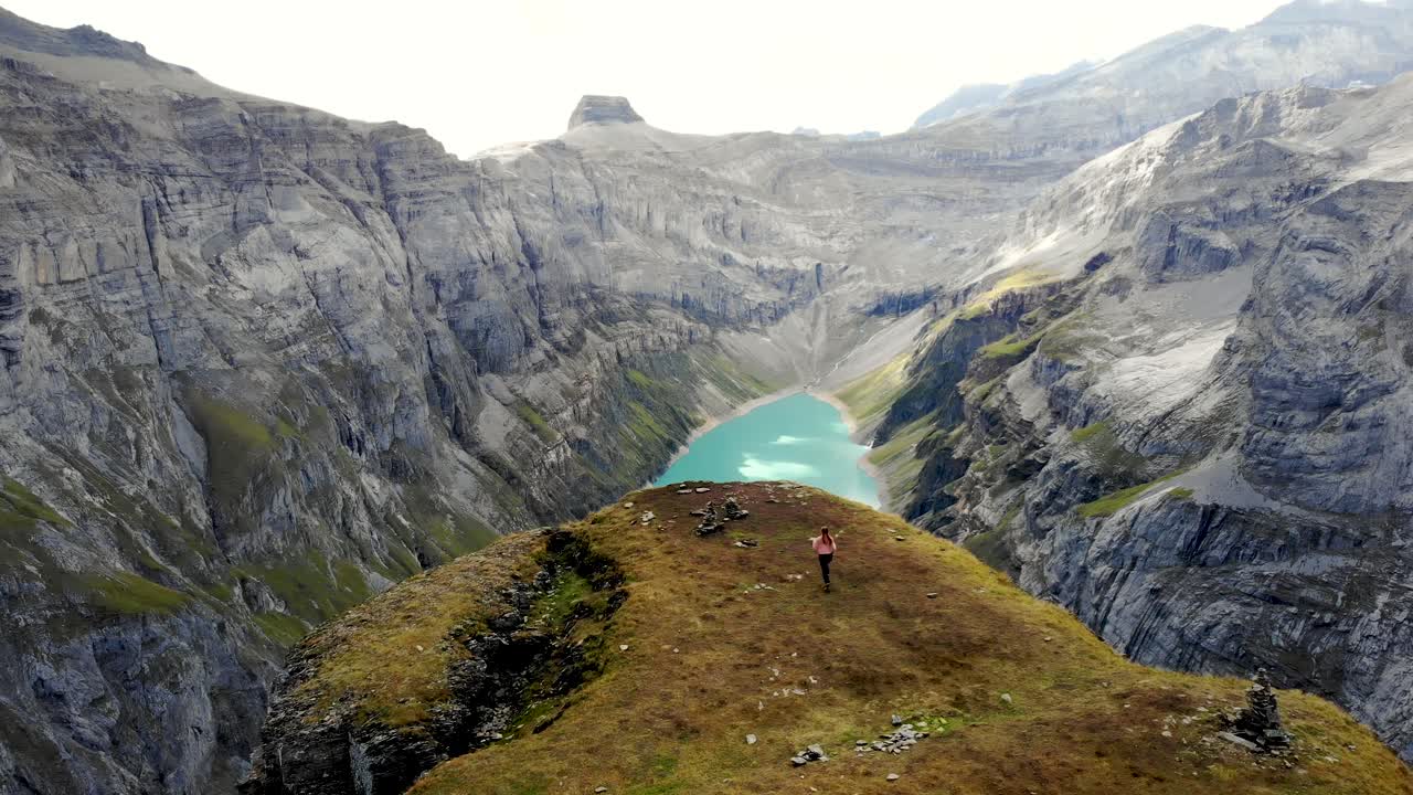 un excursionista corriendo hacia el mirador del lago limernsee en glarus, suiza, cuyas aguas color turquesa están rodeadas de altos picos y acantilados de los alpes suizos