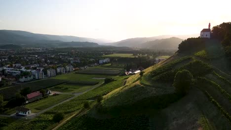 video de drones aéreos cerca de la iglesia en la cima de una colina, cerca de campos de vino, campos de maíz, huertos de manzanas en europa