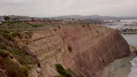 aerial footage over the beautiful red cliffs at dana point in san jan capistrano, orange county, california revealing the harbor and dana cove