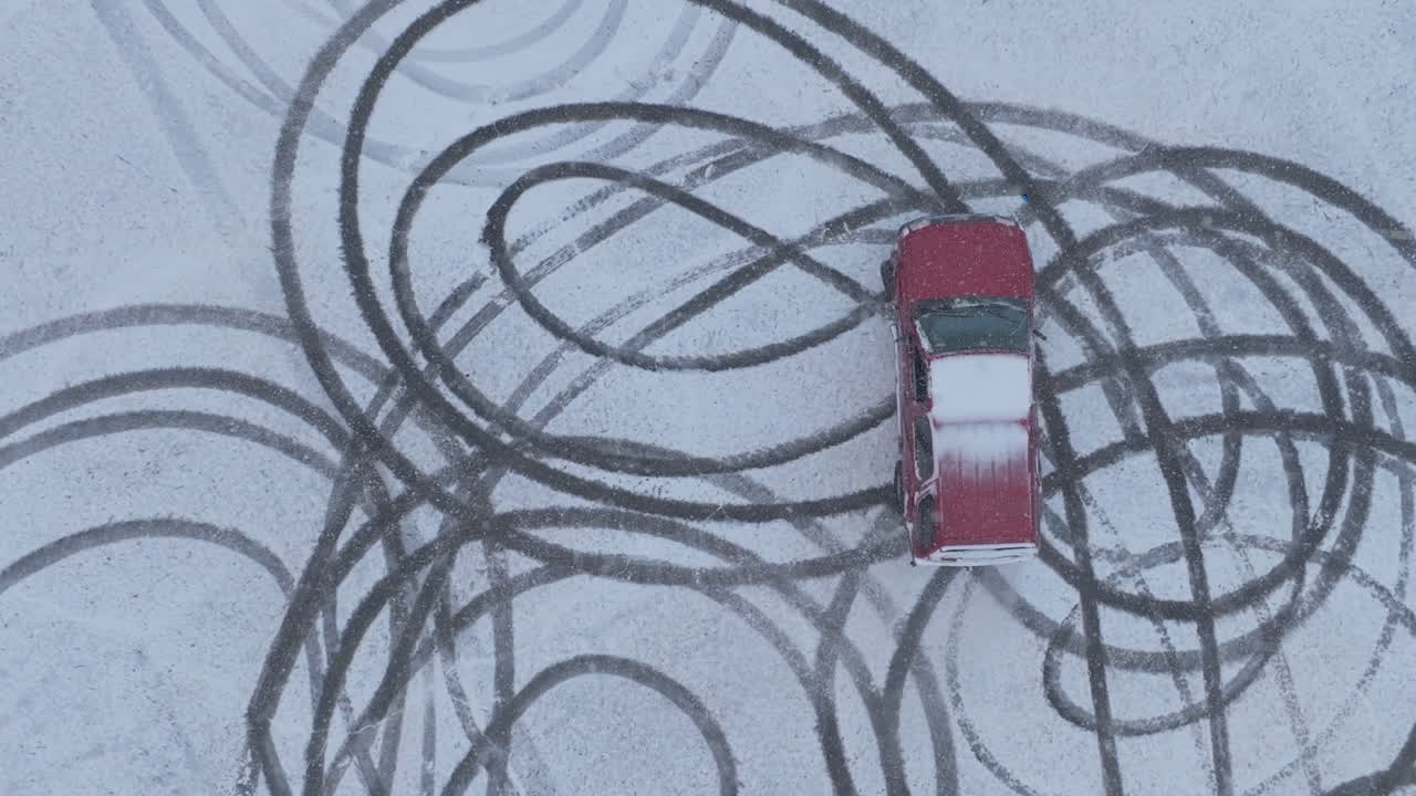 Slow motion top down aerial footage of a suv doing donuts in a parking lot covered in snow in Chattanooga, TN.