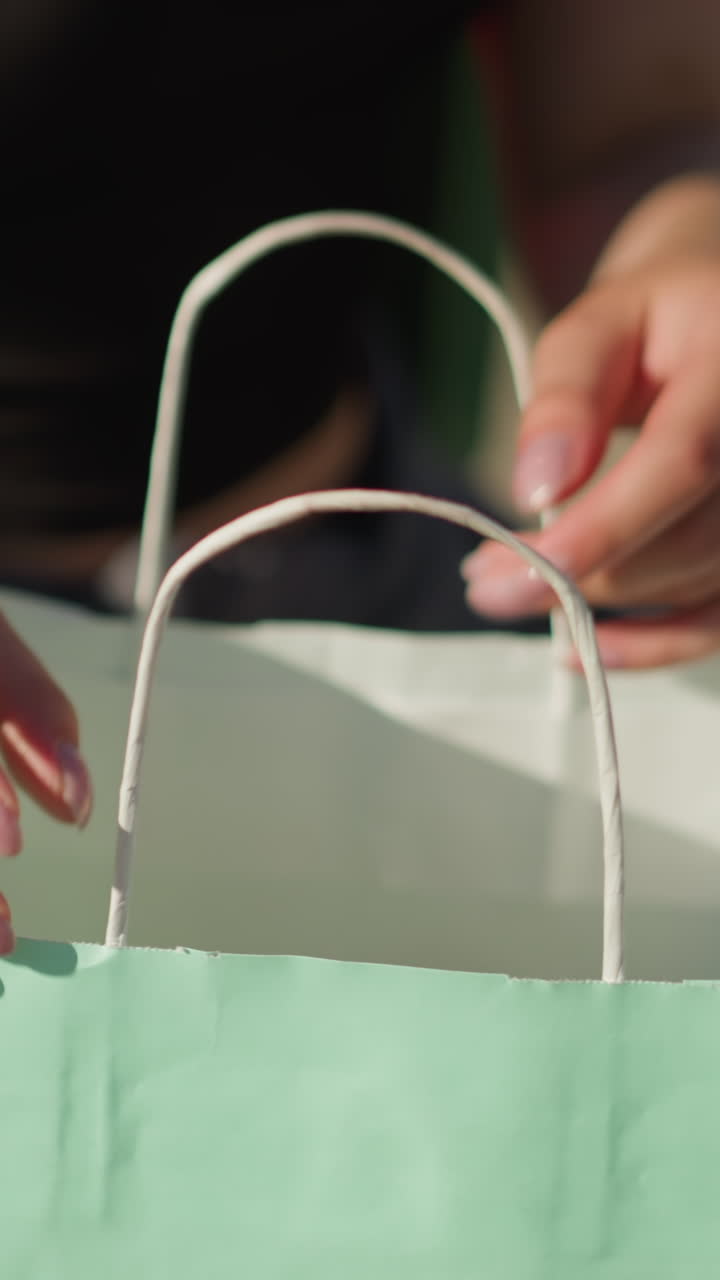 멘트 녹색 쇼핑 가방을 통해 검색하고 멘트 색의 책을 가져오는 여자의 손의 클로즈업, 배경은 그녀가 그녀의 검색을 계속하는 동안 약간 흐릿하게 보여줍니다.