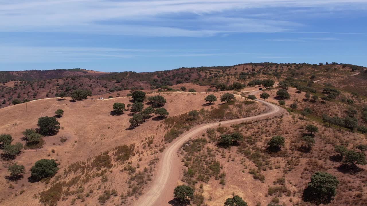 uma vista da estrada de terra sinuosa em colinas e montanhas inclinadas no alentejo, portugal
