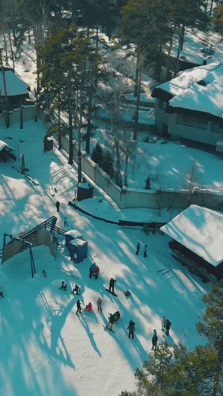 mountain flat top with modern ski resort and people on wide snowy track against blue sky at sunlight upper view