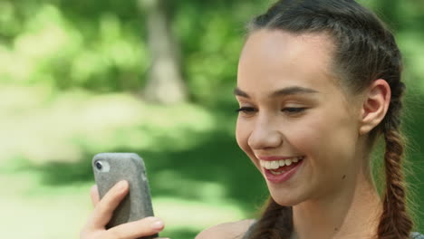 cheerful woman using mobile phone while morning run in summer park