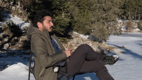 hombre descansando y tomando café en la nieve