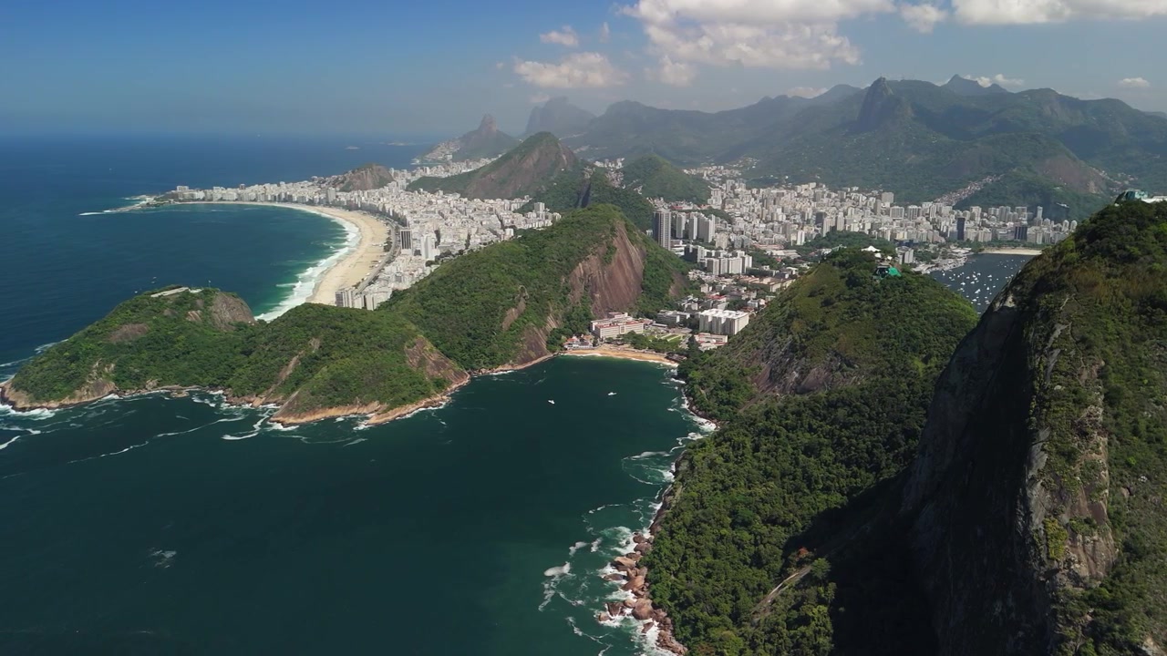 Il drone si alza e si allontana per rivelare Rio de Janeiro, spiagge, baie, il Pan di Zucchero e lo skyline della città.