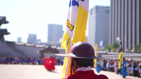 Slow-motion-behind-royal-guard-with-flag-during-traditional-ceremony,-Gyeongbokgung