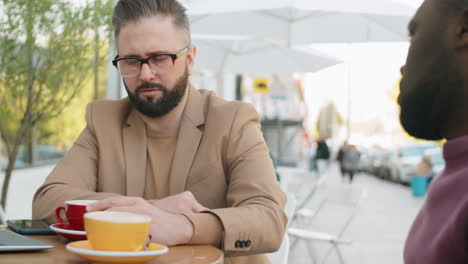 Hombres-Multiétnicos-Hablando-Y-Tomando-Café-En-Un-Café-Al-Aire-Libre