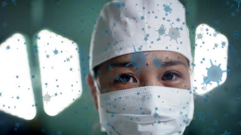 animation of floating viruses over asian female surgeon waring cap and mask in hospital