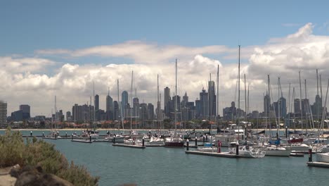 static wide shot showing marina with docking sailing boats and skyline of melbourne in background,australia