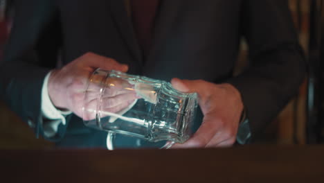 bartender wipes glass mug standing at counter in pub