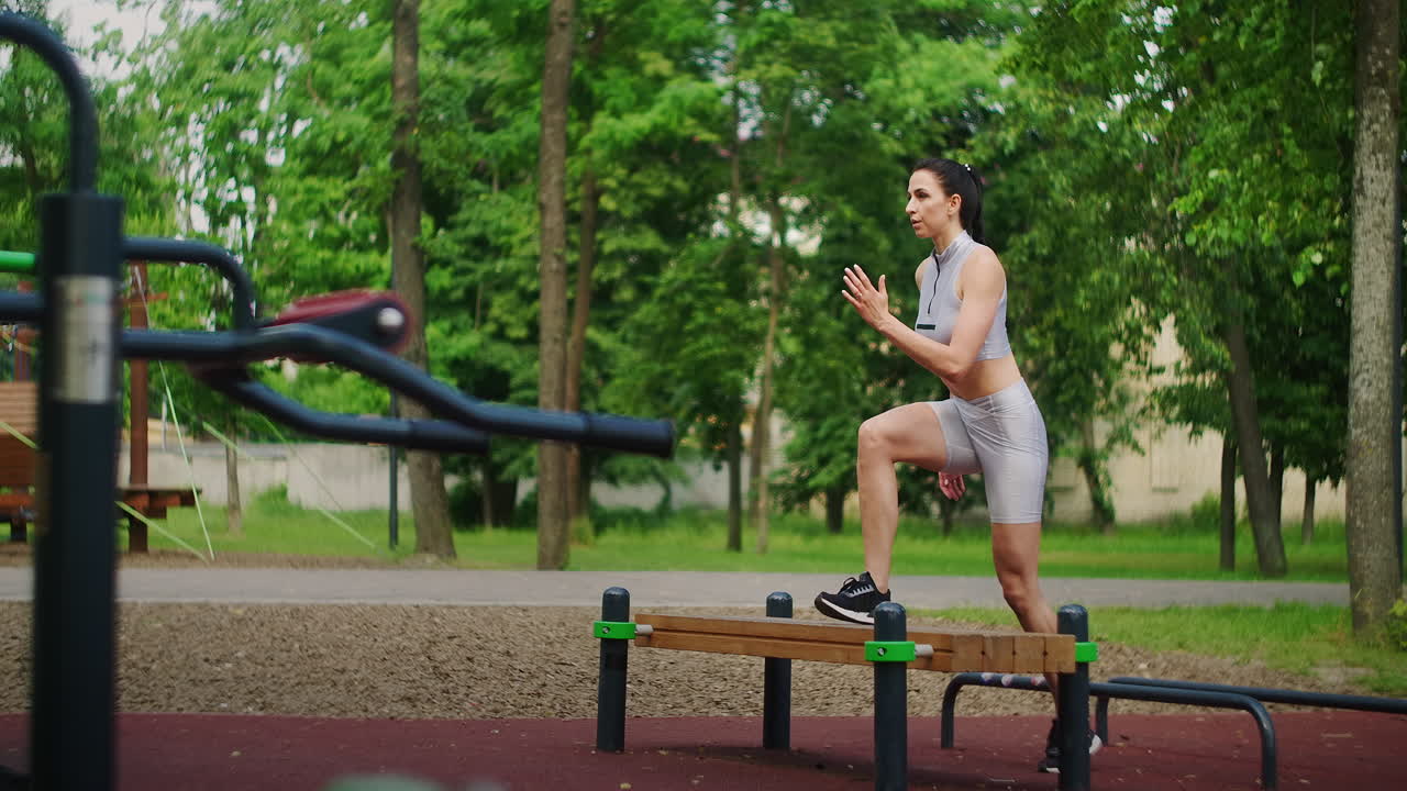 A beautiful woman walks on a bench during a training session in a Park in summer in slow motion