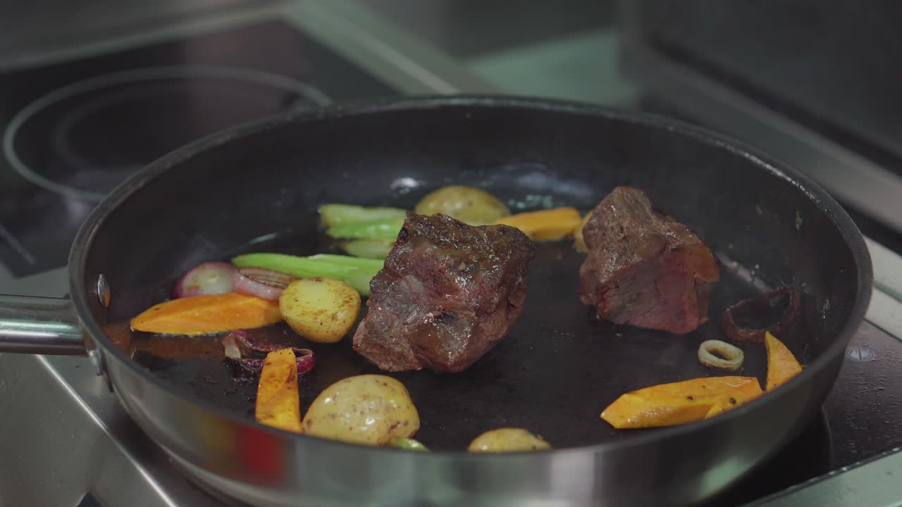 요리사는 채소로 스테이크를 요리하고 있습니다.