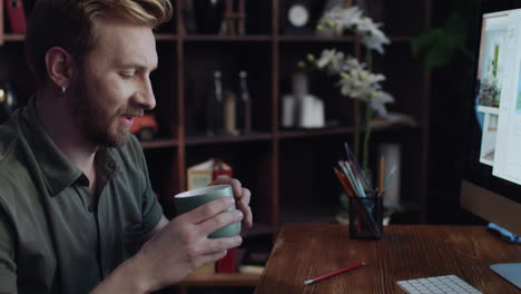 upset man designer taking empty cup at desk in creative workshop