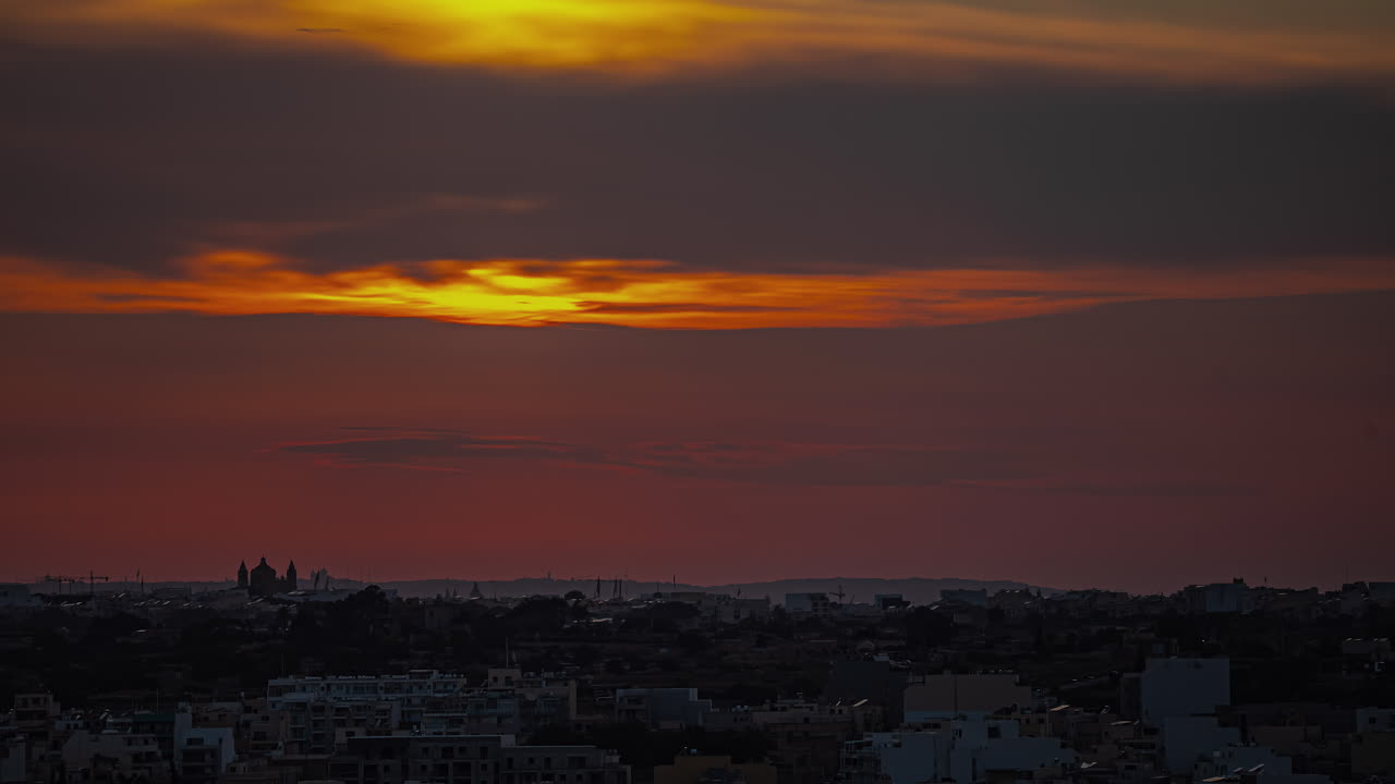 el sol rompe a través de las nubes en un resplandor naranja al atardecer en malta