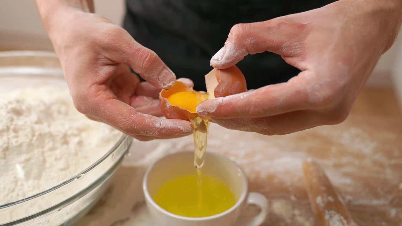 Close-up of Hands Cracking and Separating an Egg for Baking