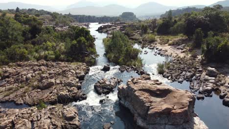 Volando-Sobre-El-Pintoresco-Río-Que-Fluye-A-Través-De-Las-Rocas-En-Las-Montañas-Drakensberg-En-Sudáfrica