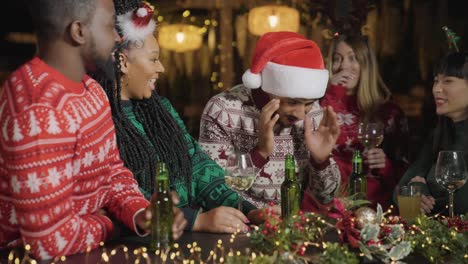 tracking shot pulling away from group of friends celebrating christmas at bar