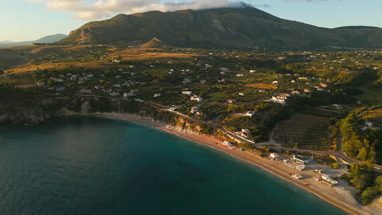 Aerial drone orbiting over empty Guidaloca Beach in Sicily, Italy, showcasing stunning coastline, greenery, and serene natural scenery