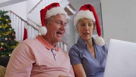 Happy-caucasian-senior-couple-having-video-call-at-christmas-time