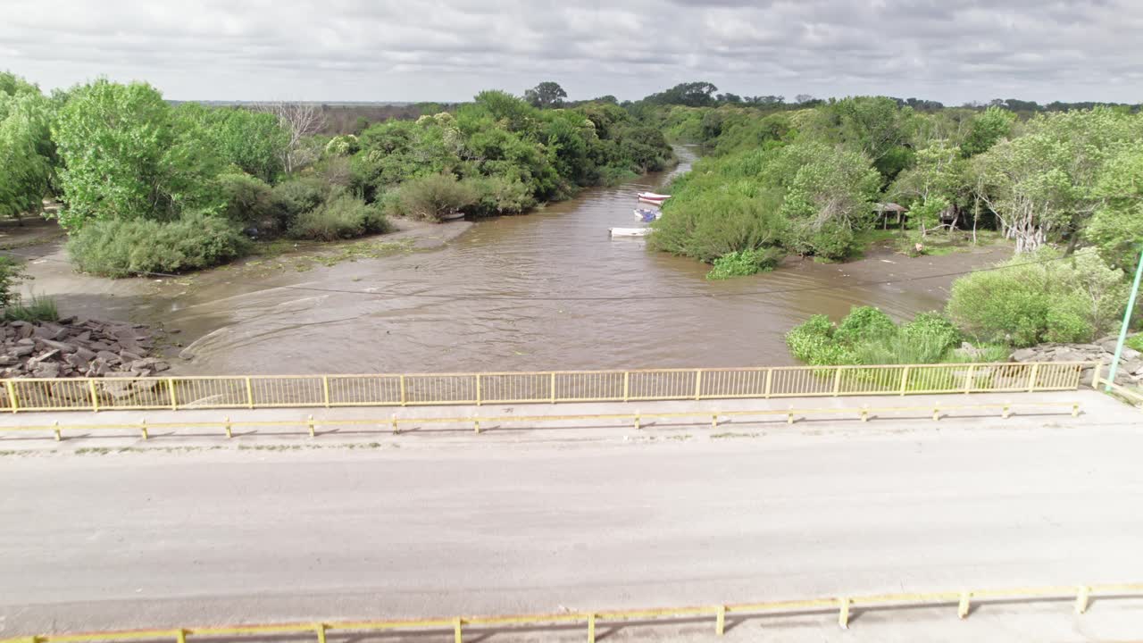 Drone footage capturing a bridge over the Rio de La Plata, with lush green trees along the riverbanks.