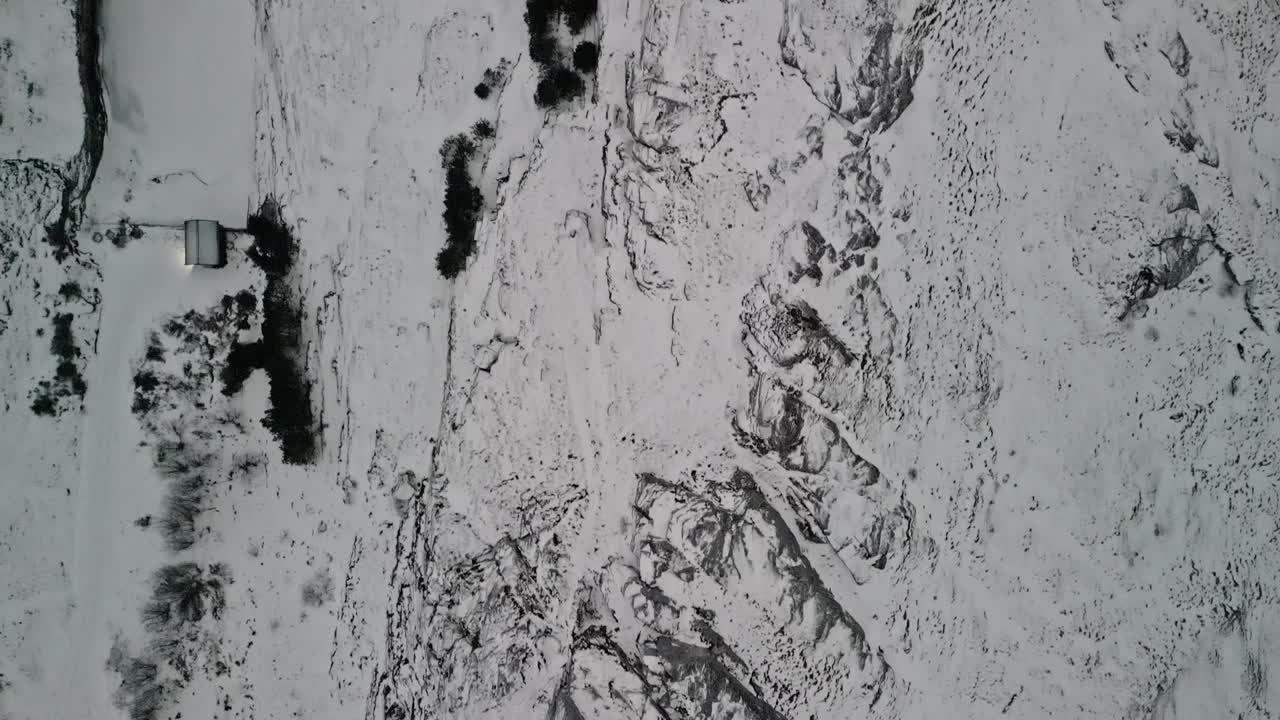 drone atravesando un paisaje invernal blanco con rocas y árboles hasta que se encuentra con el océano