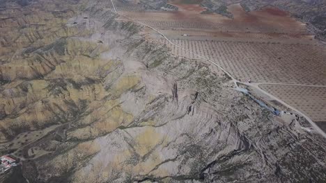 Aerial-view-of-a-badlands-desert-area-with-a-dirt-road-and-a-big-ravine