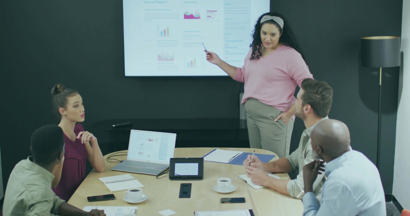 Presentatore che tocca il display, inserendo icone animate di dispositivi in sovrapposizioni grafiche durante una riunione di lavoro.