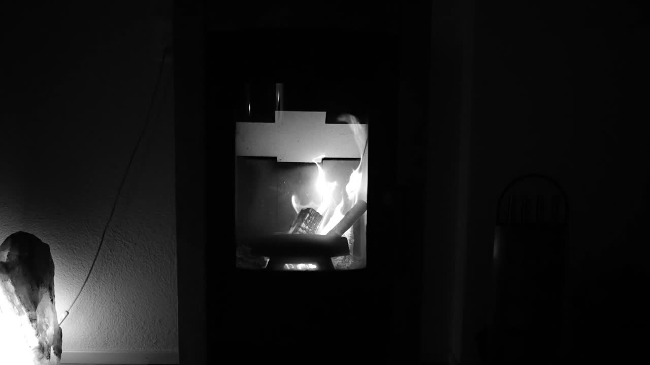 Black and white image of a fireplace with burning logs.