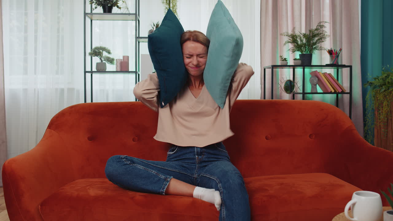 trabajo de reparación en los vecinos concepto, mujer irritada en casa cubrir las orejas con almohadas molestado por el ruido