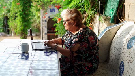 Ältere-Frau-Benutzt-Laptop-Am-Tisch-Im-Garten