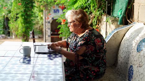 aged female using laptop at table in garden