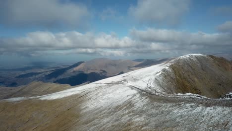 aerial cinematic view of autumn snow accumulated mountain top in a sunny day with some clouds moving