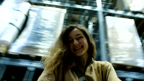 cheerful woman is spinning with a cart in the warehouse of a shopping center