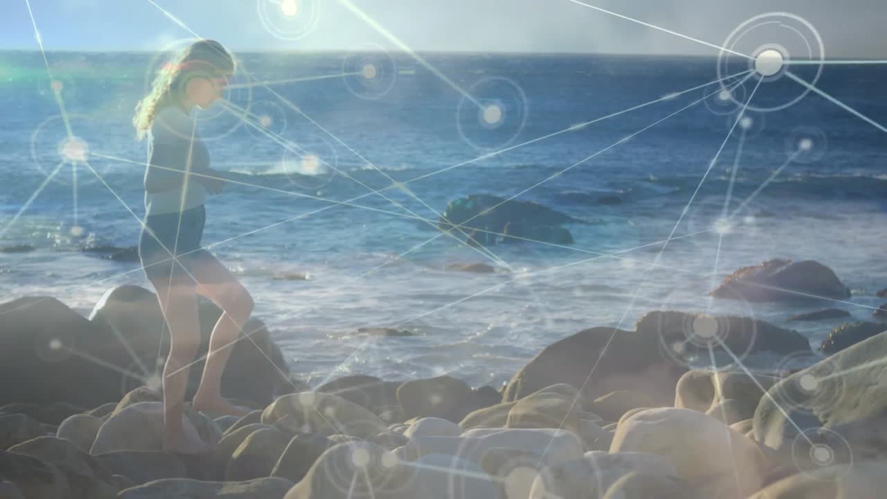 Adjusting chest sensor, woman navigating rocky shore initiating nodes extending showing data flow