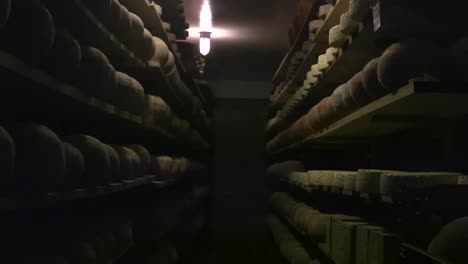 imágenes que se mueven lentamente hacia adelante en un patrón recto en una habitación o una sala de almacenamiento llena de discos de queso o bolas que están débilmente iluminadas